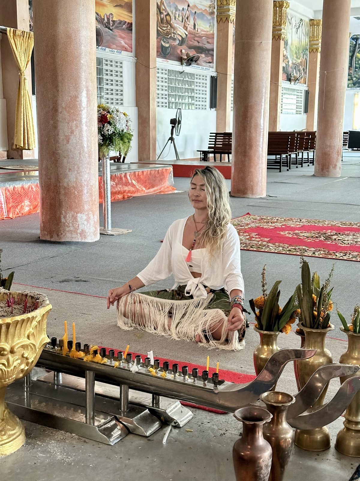 Olga meditando en un templo en Tailandia, rodeada de velas